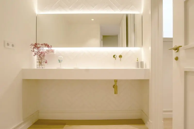 Baño con lavabo suspendido y grifería dorada