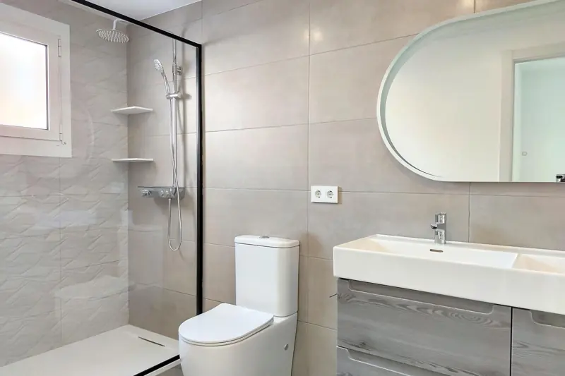 Baño gris con espejo ovalado